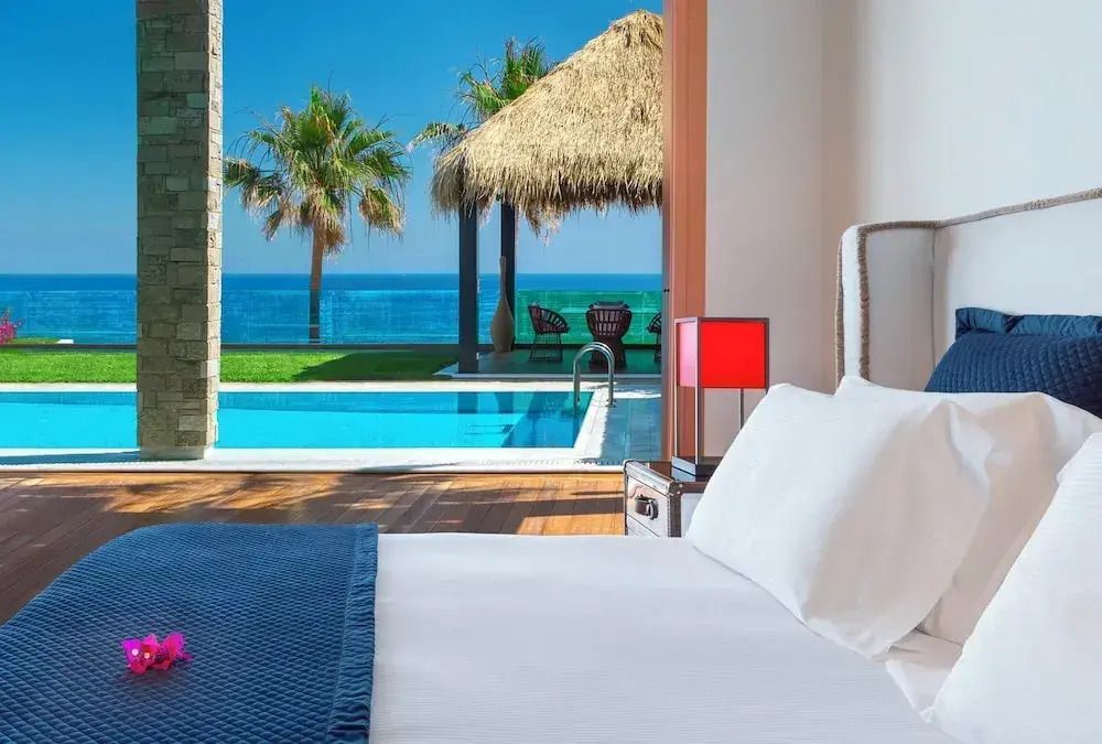 Schlafzimmer mit Blick auf privaten Pool und Meer mit Palmen