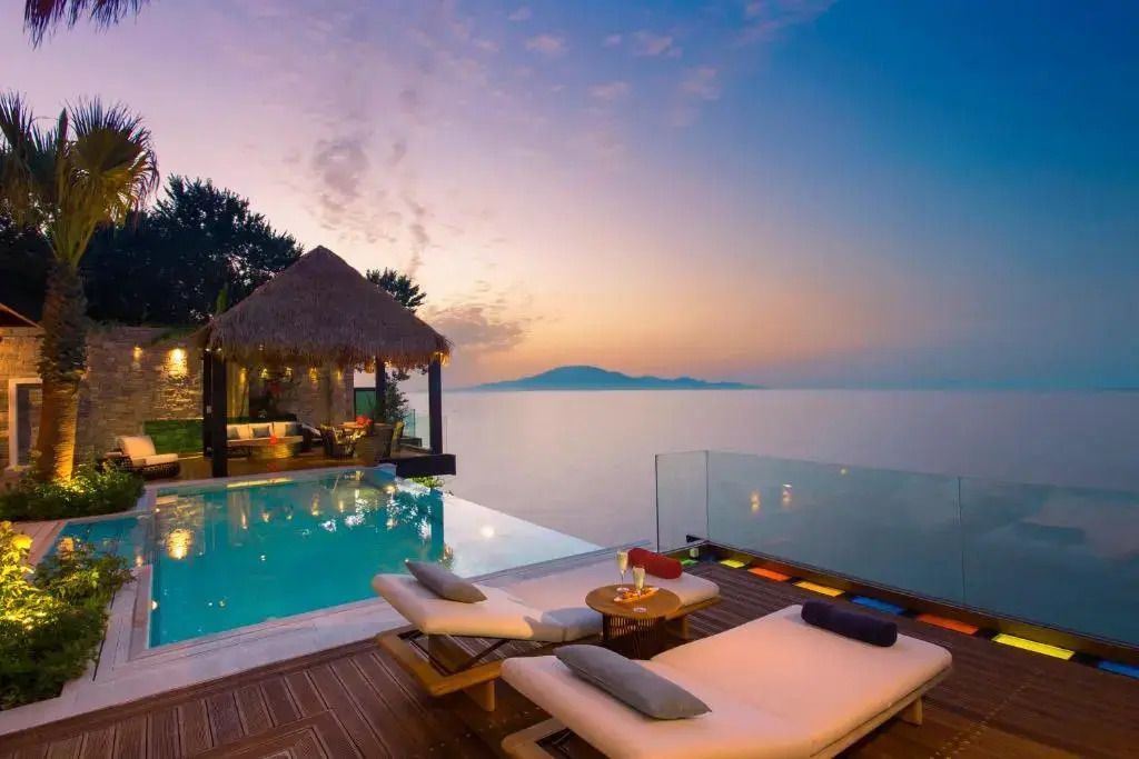 Infinity-Pool und Lounge-Bereich mit Meerblick am Abend