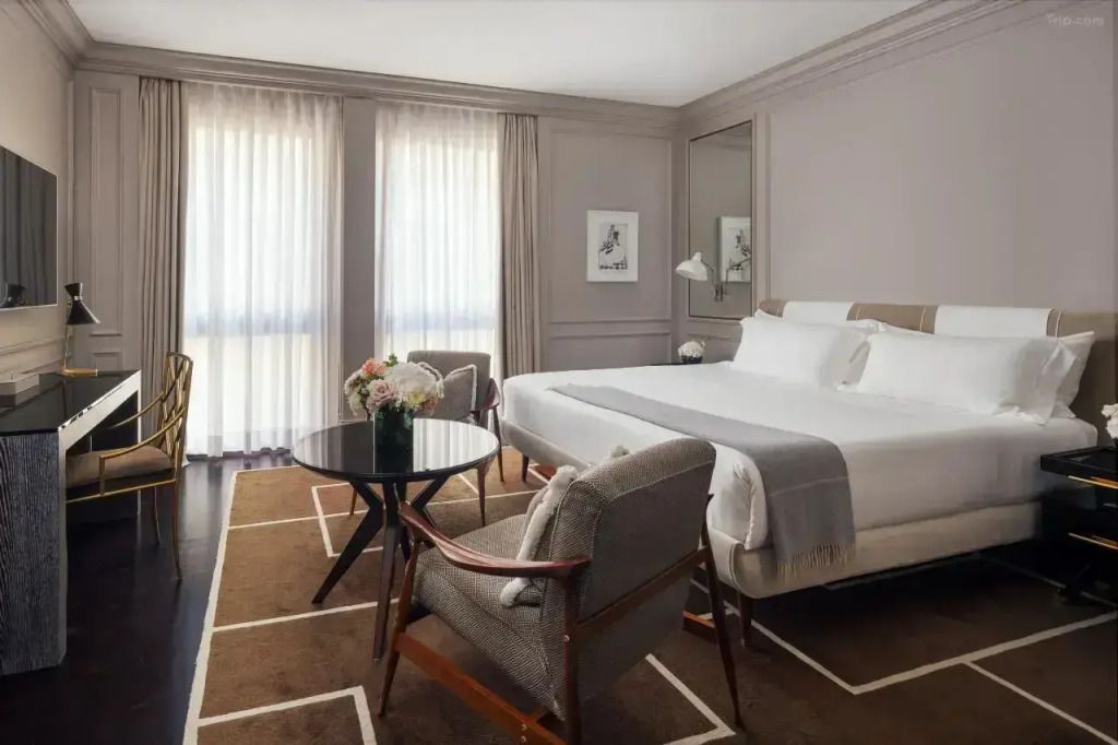 Elegantes Doppelbett in einem modernen Hotelzimmer mit Sitzbereich und natürlichem Licht.