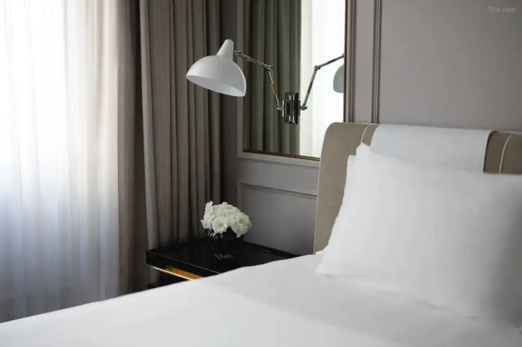 Nahaufnahme eines stilvollen Bettes mit weißen Blumen und einer Designerlampe.