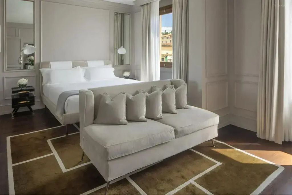Elegantes Schlafzimmer mit Doppelbett und Sofa, Blick auf den Arno in der Suite.