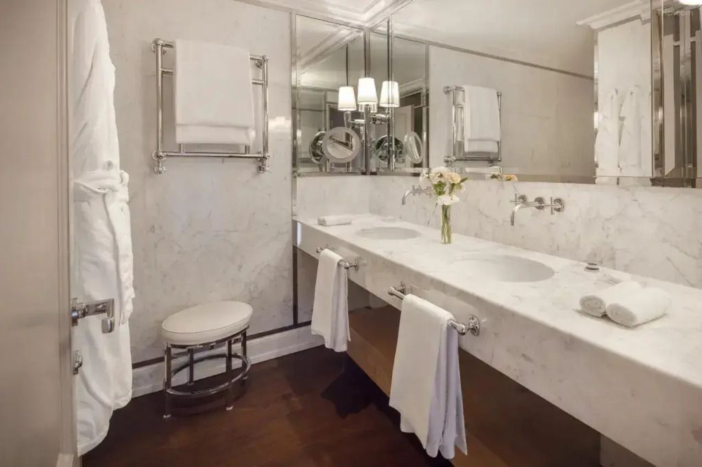 Luxuriöses Badezimmer mit Doppelwaschbecken aus Marmor und eleganter Beleuchtung.