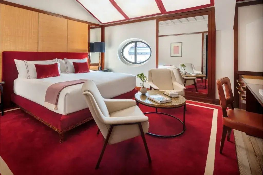 Geräumiges Deluxe Studio mit Doppelbett, rotem Teppich und eleganten Möbeln.
