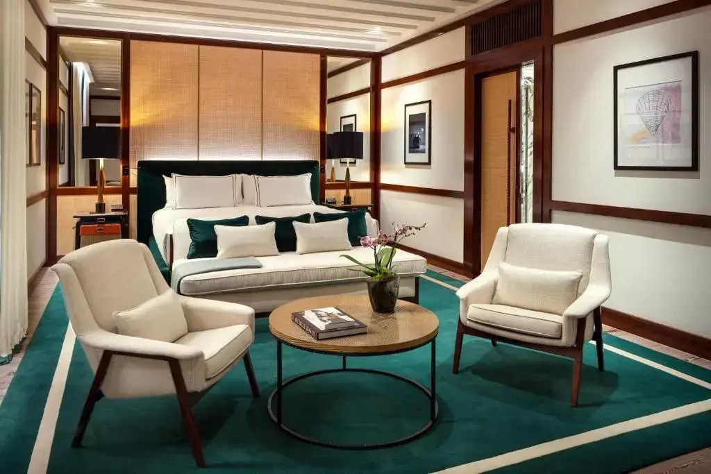 Elegantes Doppelbett und Sitzbereich in Suite mit grünen Akzenten