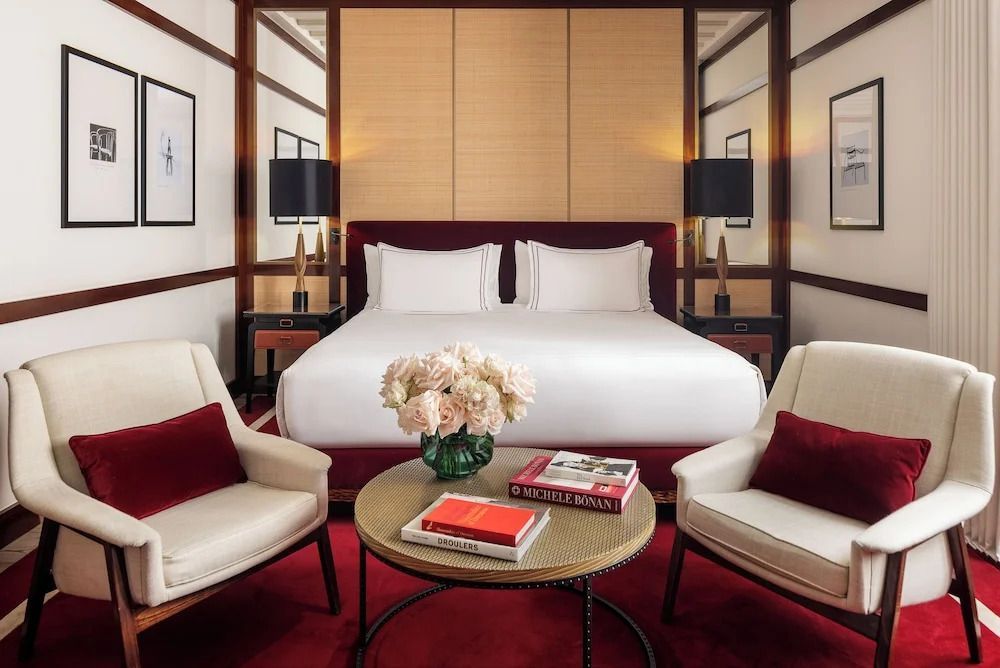 Elegantes Schlafzimmer mit großem Bett und stilvollen Sesseln in warmen Tönen