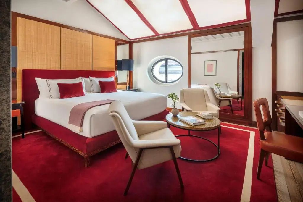 Geräumige Suite mit rotem Teppich, Doppelbett und großen Fensterspiegeln