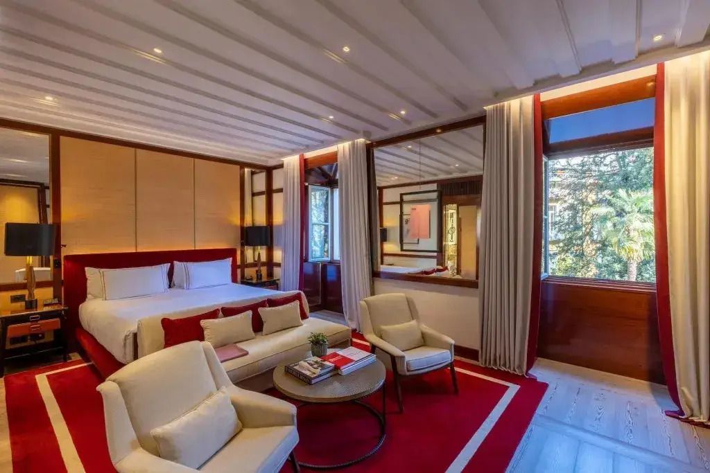 Suite mit gemütlicher Sitzecke, roten Kissen und großem Fenster