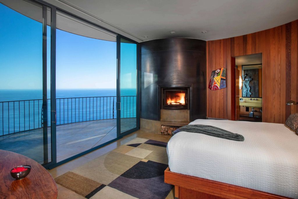 Gemütliches Schlafzimmer mit Kamin und Balkon mit Blick auf den Ozean