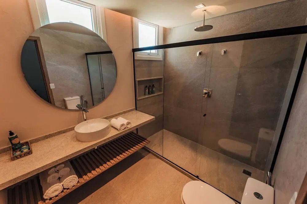 Luxuriöses Badezimmer mit Regendusche und rundem Spiegel