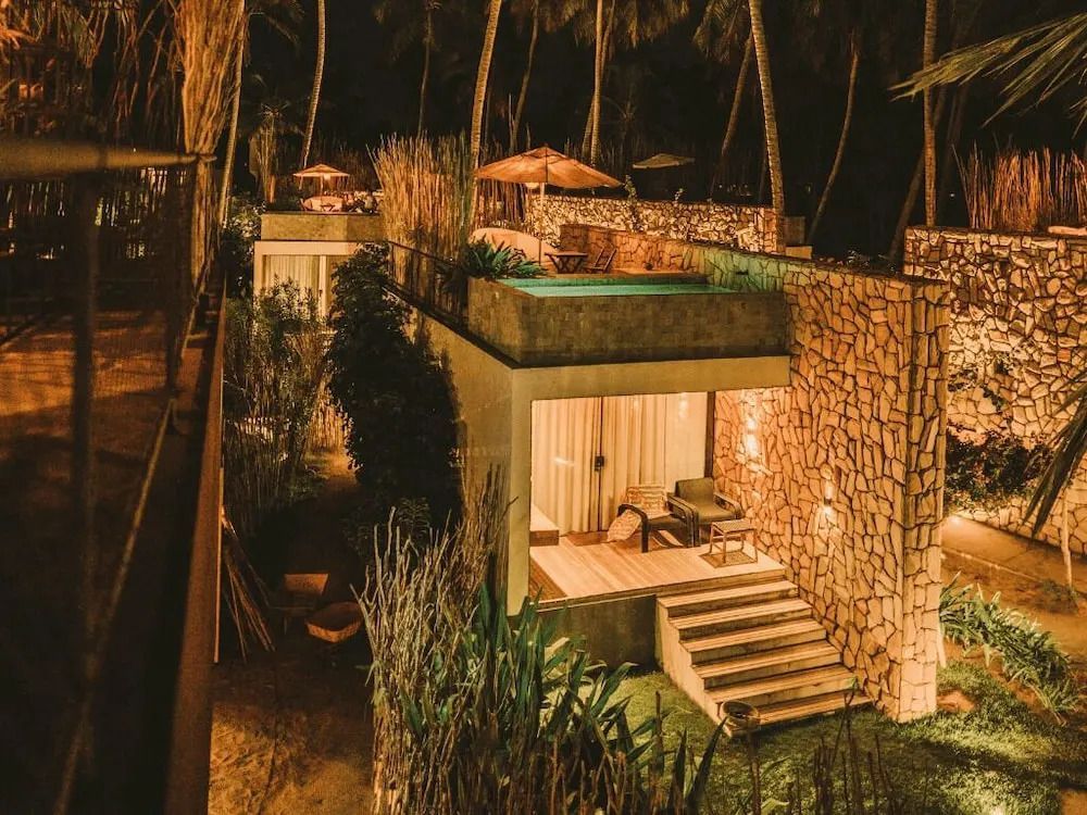 Villa mit privatem Pool im Licht der Nacht umgeben von tropischer Vegetation