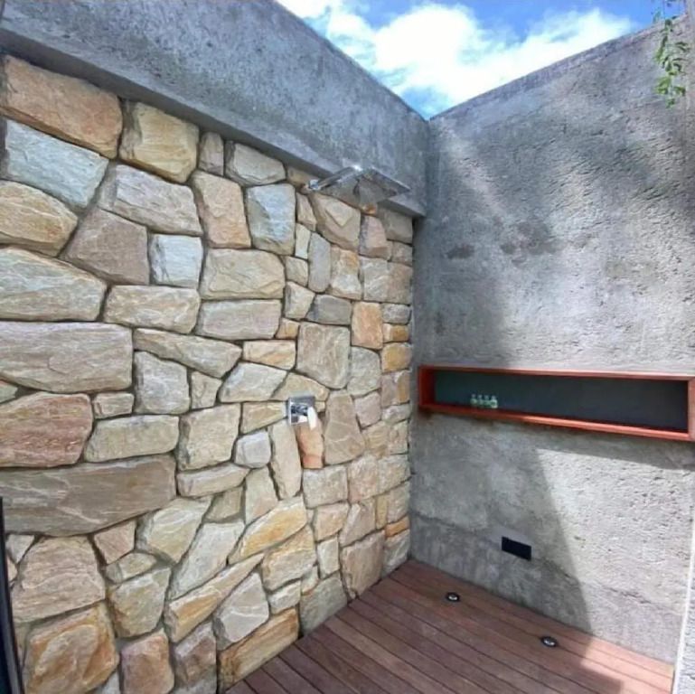 Dusche mit Natursteinwand und Holzboden im Freien