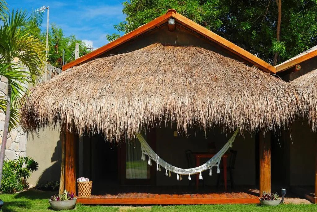 Rustikaler Bungalow mit Reetdach und Hängematte im Garten