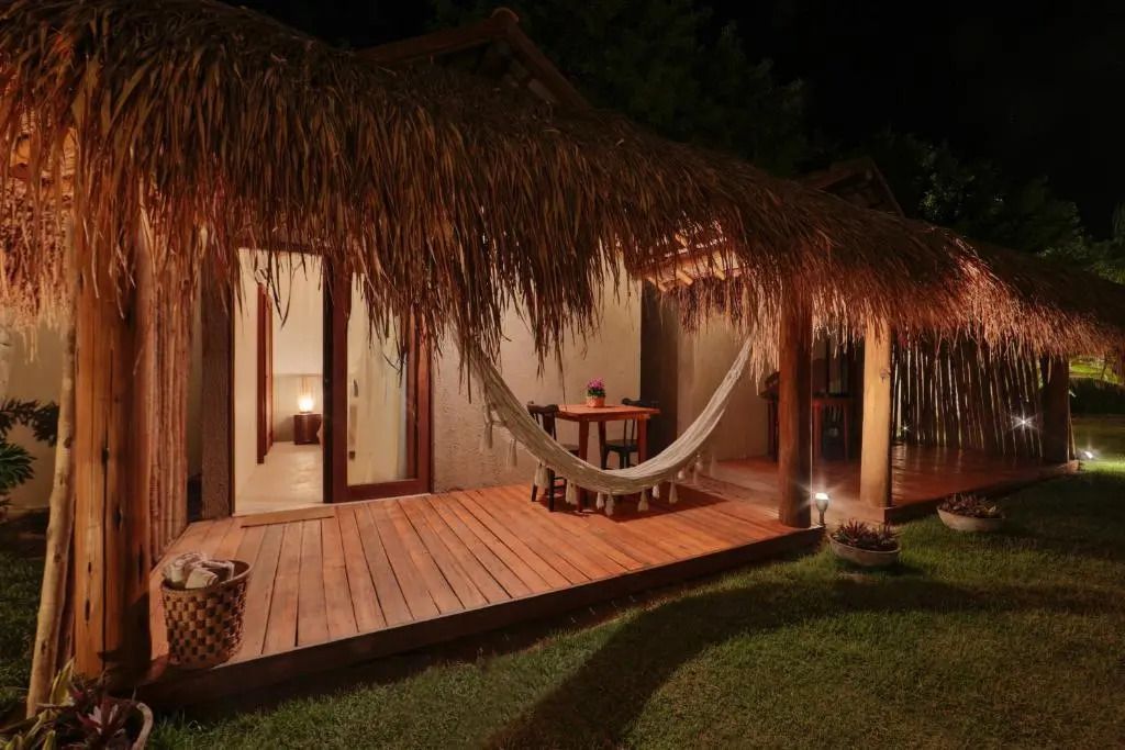 Bungalow abends beleuchtet mit Hängematte und Holzboden