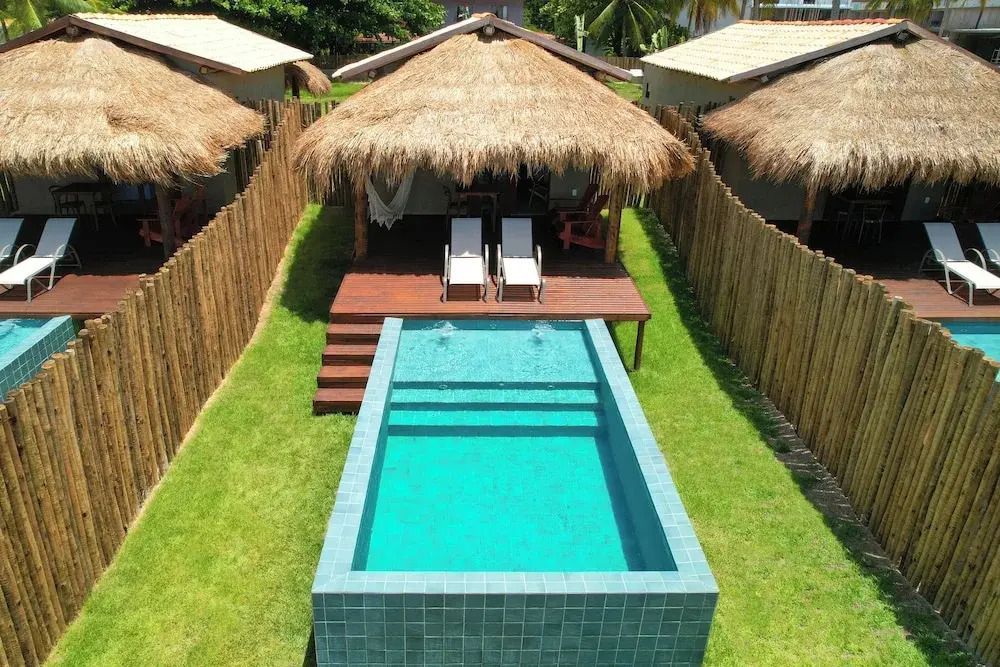 Premium Bungalow mit Strohdach und privatem Pool umgeben von einem grünen Garten