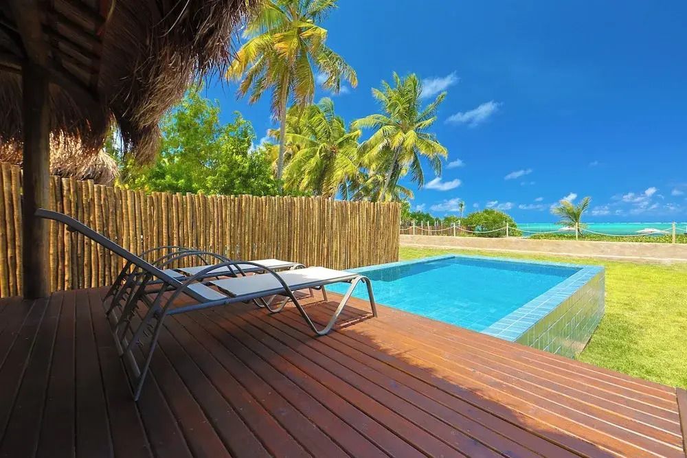Sonnendeck mit Liegestühlen am privaten Pool umgeben von Palmen