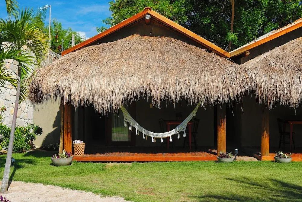 Bungalow mit Hängematte und Strohdach in tropischer Umgebung