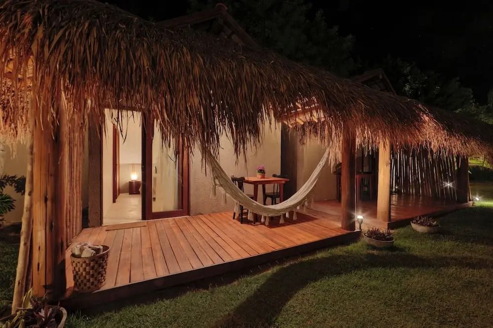 Bungalow mit Holzterrasse Hängematte und abendlicher Beleuchtung