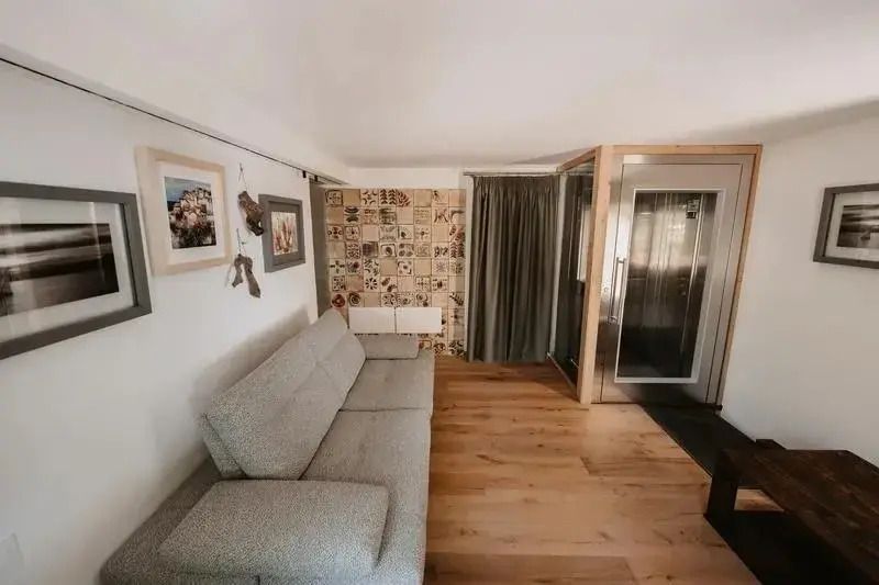 Wohnbereich der Deluxe Suite mit grauem Sofa und kunstvoller Wanddekoration