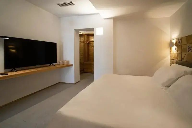 Modernes Doppelzimmer mit minimalistischer Einrichtung und großem Fernseher