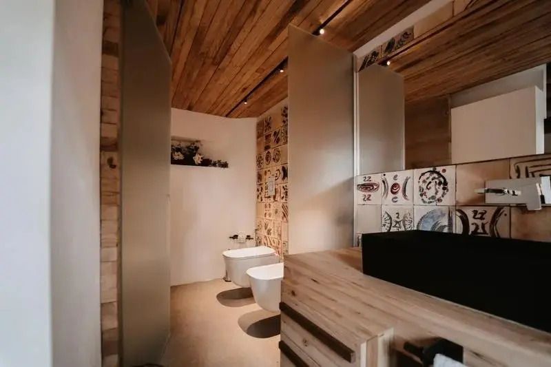 Elegantes Badezimmer mit Holzakzenten und kunstvoller Fliesenwand