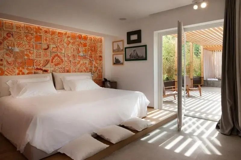 Helles Schlafzimmer mit Doppelbett und Zugang zur begrünter Terrasse