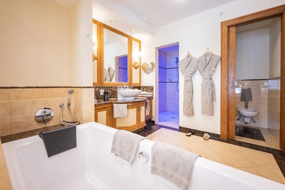 Geräumiges Bad mit Badewanne und zwei Bademänteln an der Wand