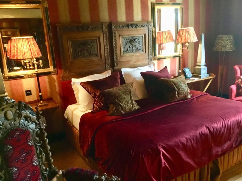 Luxuriöses Zimmer mit opulenter roter Bettwäsche und Holzverzierungen