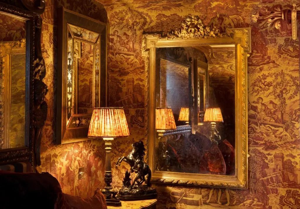 Opulent eingerichtetes Zimmer mit großen Spiegeln und kunstvollen Tapeten