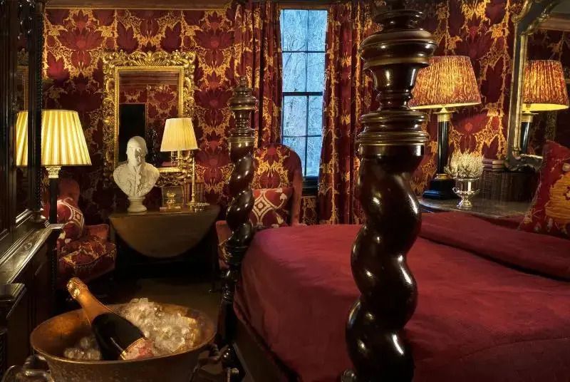 Opulentes Zimmer mit barocker Dekoration und rotem Samtbett in Prestonfield House.