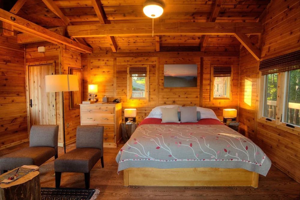 Gemütliches Schlafzimmer mit Holzwänden und Doppelbett in einer rustikalen Hütte