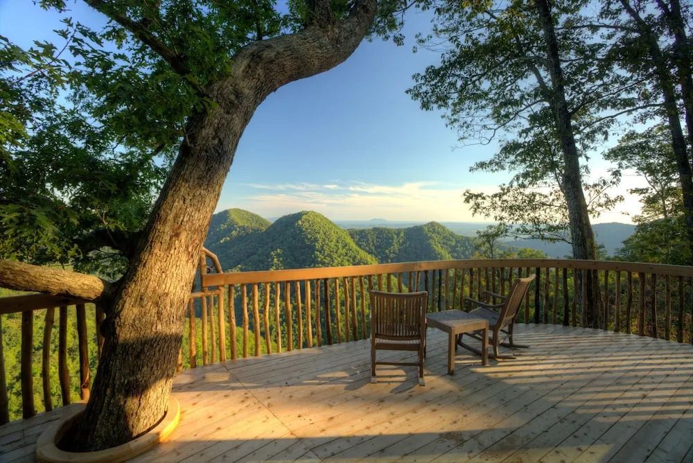 Holzterrasse mit zwei Stühlen und malerischem Blick auf bewaldete Hügel