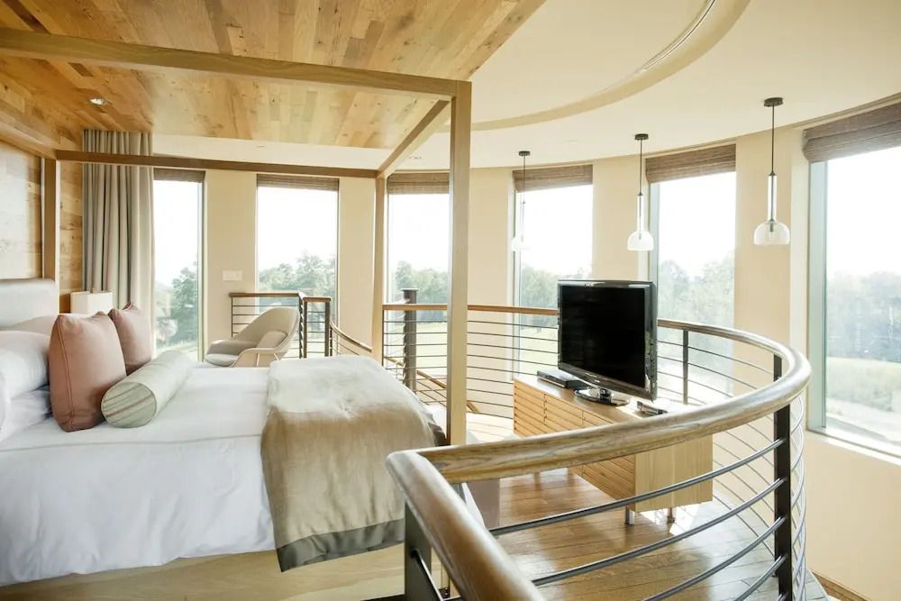Helles Schlafzimmer mit Balkon und großem Bett bietet Panoramablick durch große Fenster.