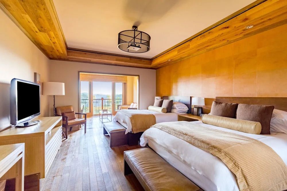 Großes Zimmer mit zwei Doppelbetten, Holzelementen und Balkonzugang