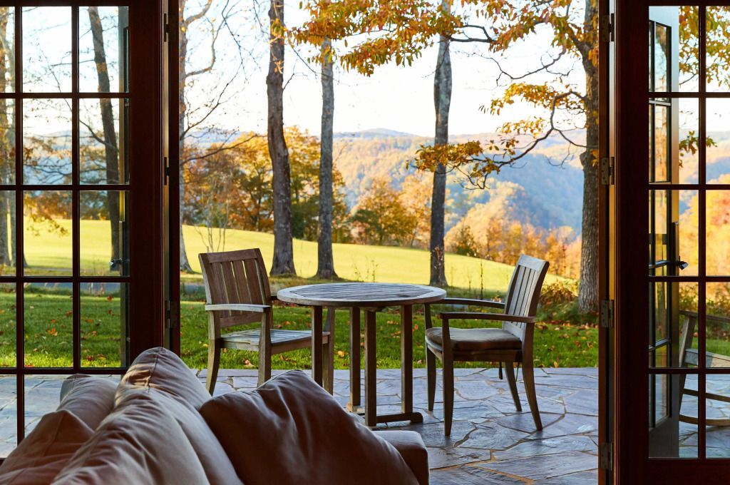 Terrasse mit Holztisch und Stühlen mit malerischem Blick auf die herbstliche Landschaft
