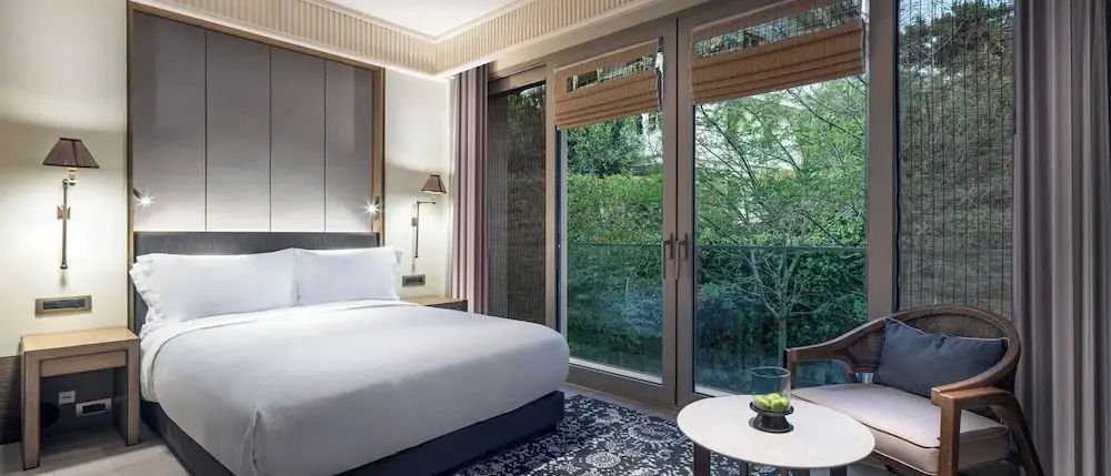 Helles Zimmer mit großem Fenster und Blick auf üppiges Grün