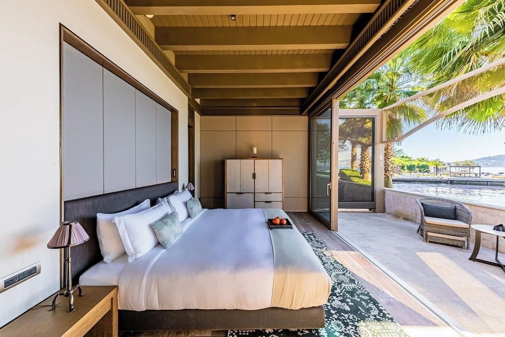 Helles Schlafzimmer in der Suite mit großem Fenster und Blick auf das Meer