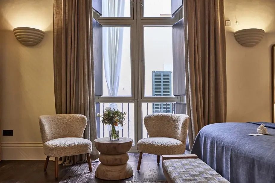 Gemütliche Sitzecke in der Suite mit großen Fenstern und stilvollen Draperien.