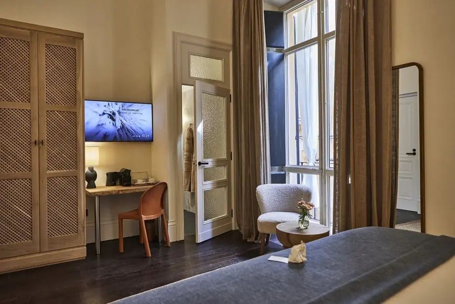 Arbeitsbereich und Sitzgelegenheit in einem eleganten Hotelzimmer neben großen Fenstern