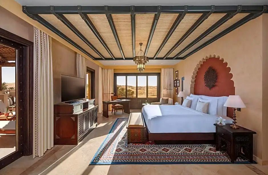 Elegantes Hotelzimmer mit Doppelbett, Fernseher und Blick auf die Wüste.