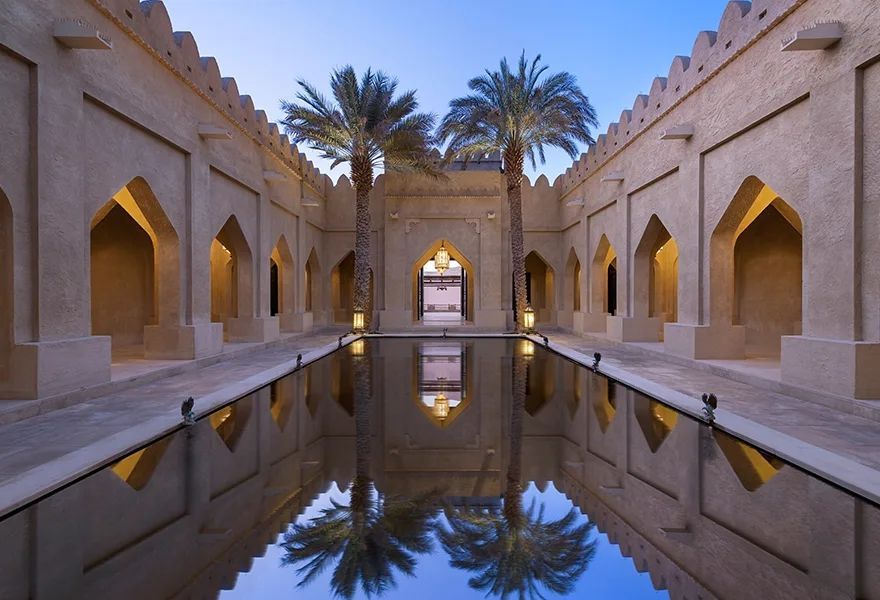 Majestätischer Innenhof mit Spiegelbecken und Palmen bei Dämmerung, inspiriert von orientalischer Architektur.