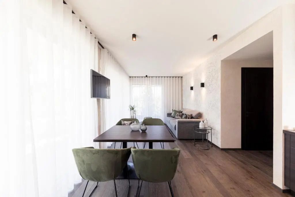 Lichtdurchflutetes Wohnzimmer mit geschmackvollen Möbeln und großem Esstisch.