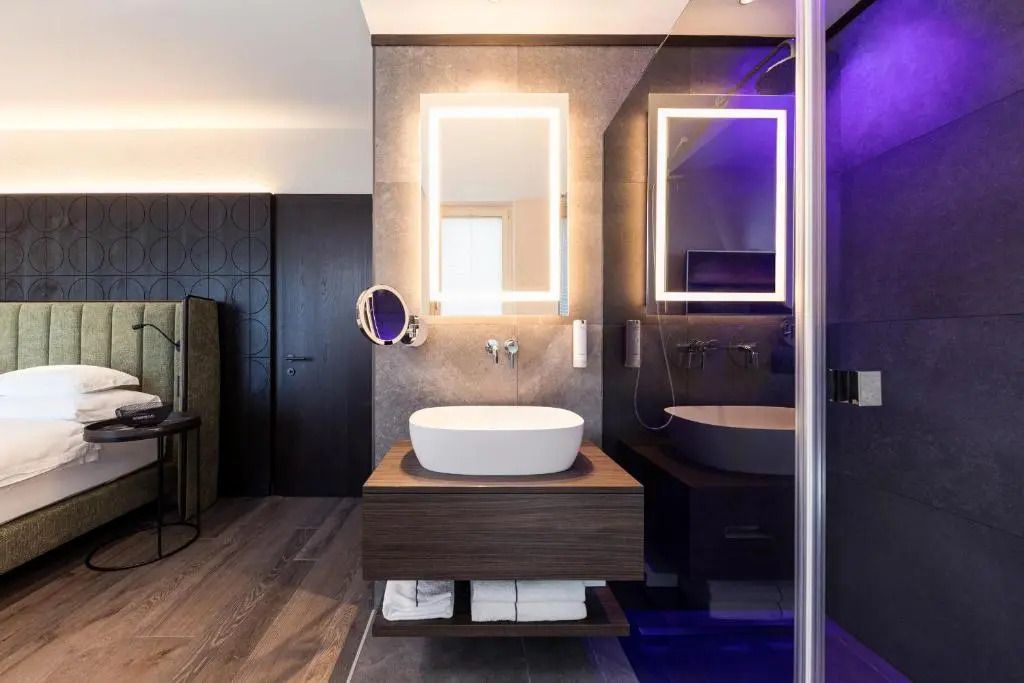 Gut beleuchtetes Badezimmer mit Waschbecken und stilvollem Spiegel im modernen Look.
