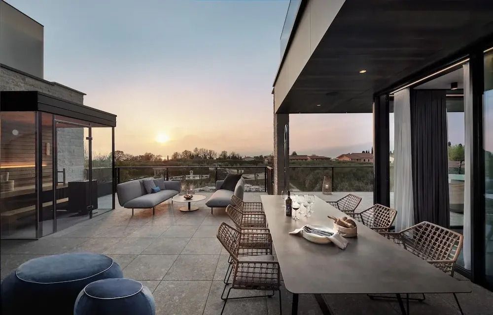 Große Terrasse mit Esstisch und Lounge-Bereich bei Sonnenuntergang