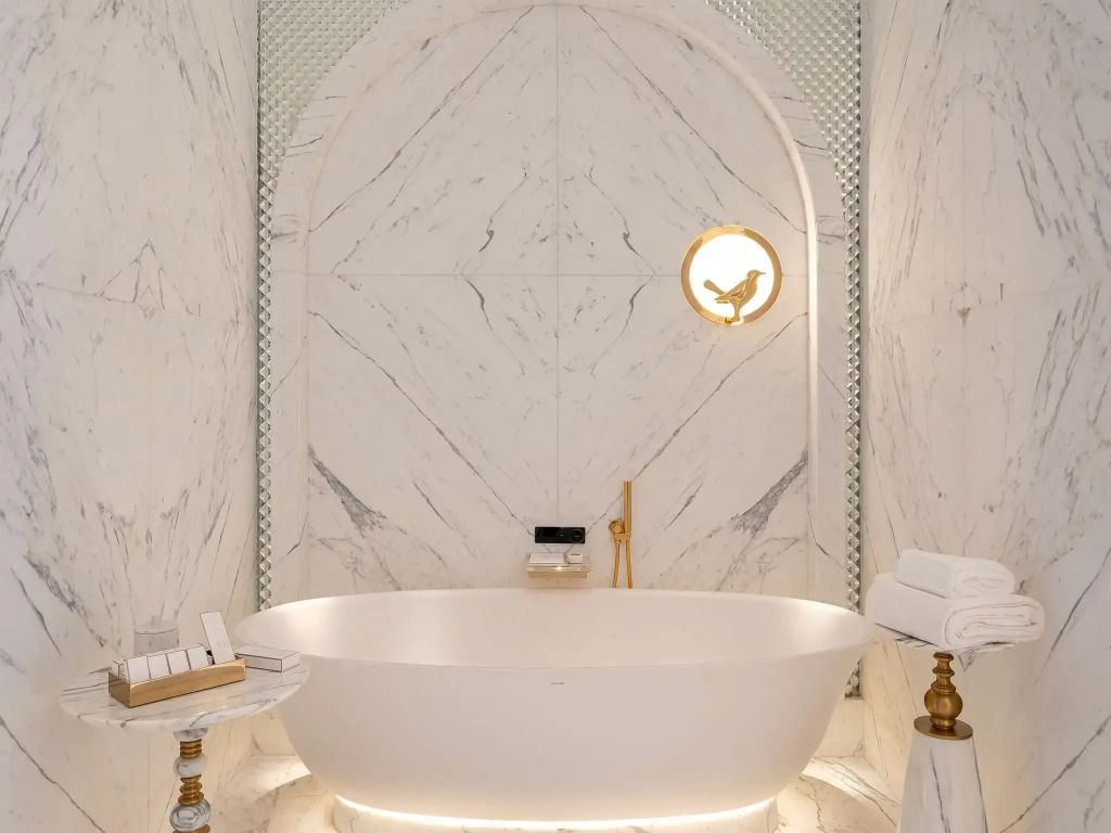 Elegantes Marmorbad mit freistehender Badewanne und goldenen Akzenten