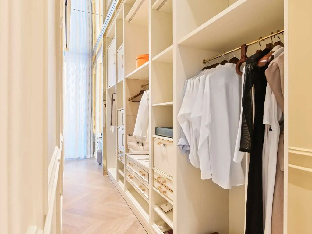 Geräumiger begehbarer Kleiderschrank mit heller Holzverkleidung in der Parisian Suite des Raffles Doha
