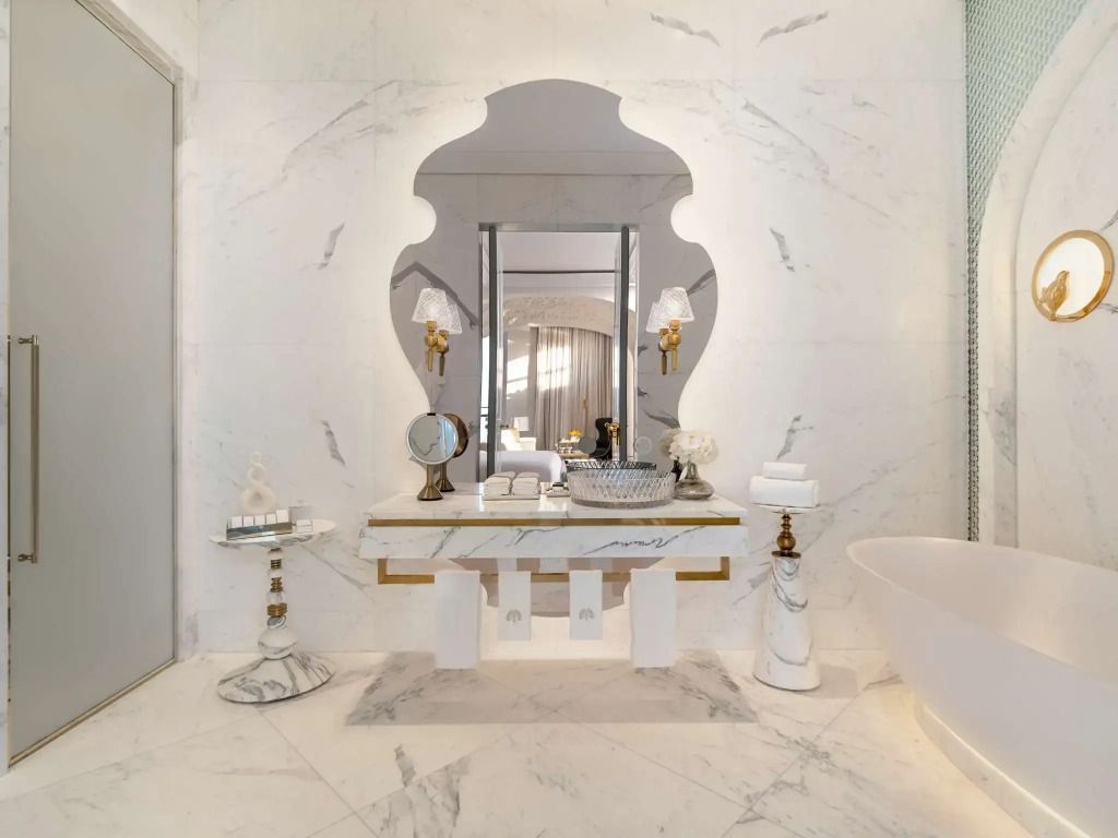 Marmorwaschtisch mit kunstvollem Spiegel und hochwertigen Accessoires im Badezimmer.