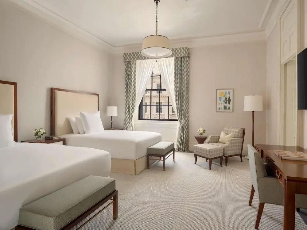 Elegantes Hotelzimmer mit zwei Einzelbetten, dekorativen Vorhängen und Sitzgelegenheit