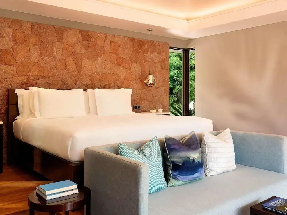 Elegantes Schlafzimmer mit Doppelbett und moderner Steinwand in der Hillside Villa.