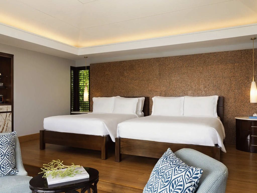 Elegantes Schlafzimmer mit zwei Doppelbetten und Holzböden in der Panoramic Vierer Pool Villa