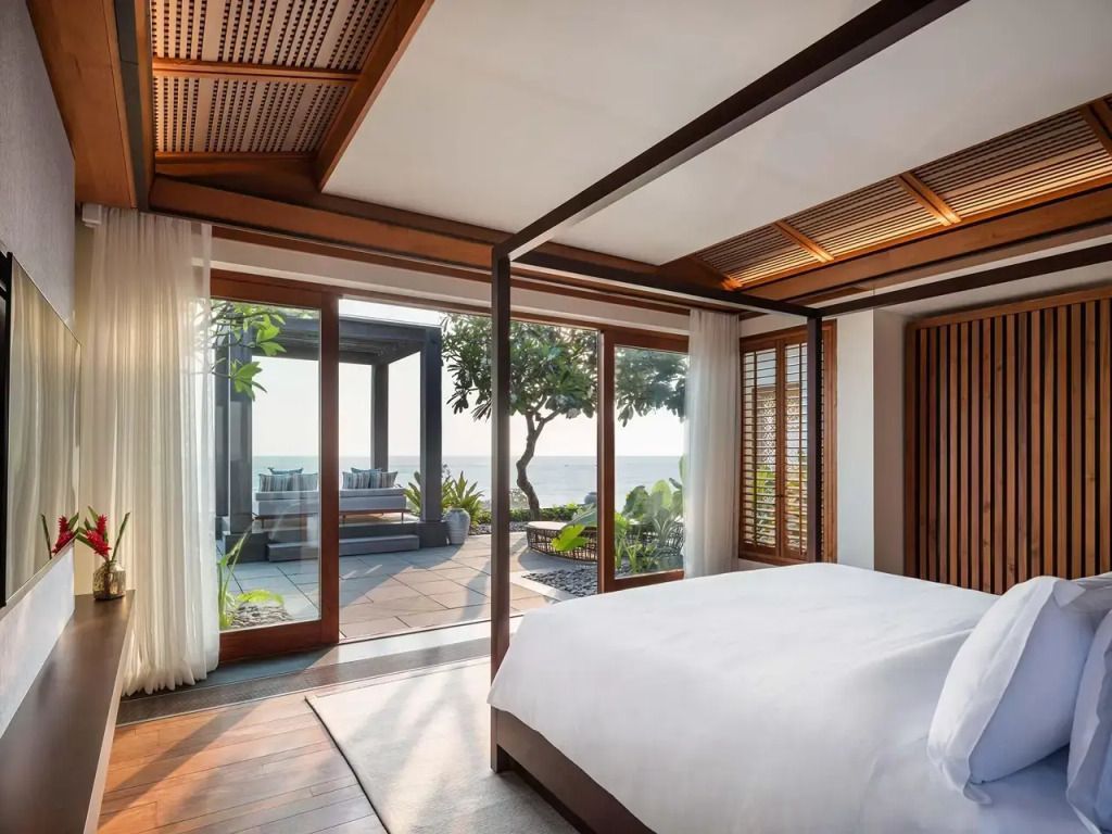 Helles Schlafzimmer mit großem Bett und Holzdetails, Blick auf Terrasse und Meer